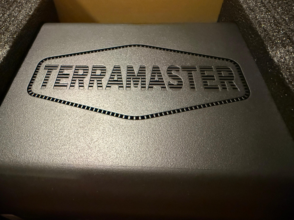 Black box packaging with "TERRAMASTER" embossed on the surface, surrounded by protective foam. The tone is sleek and industrial.
