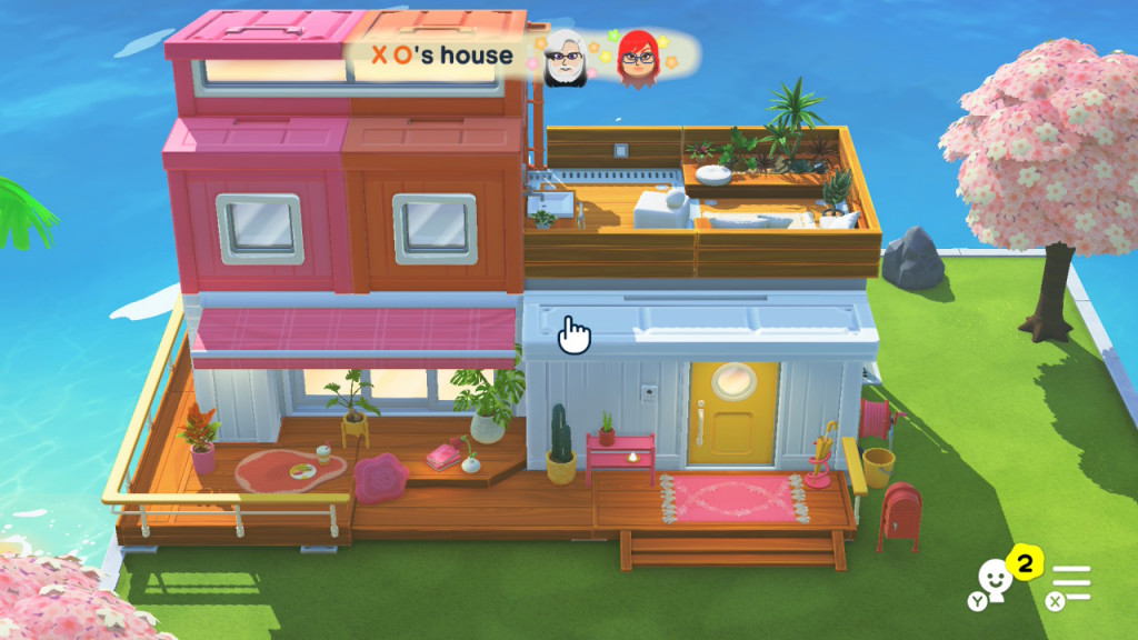 Colorful two-story virtual house with pink, orange, and white walls, rooftop plants, and cherry blossom trees on the side by the water.