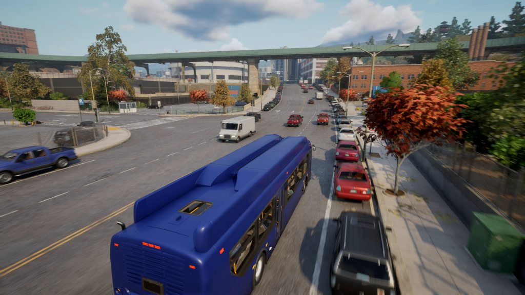 A blue, single decker bus can be seen driving down a long stretch of road. There is a queue of cars up ahead.