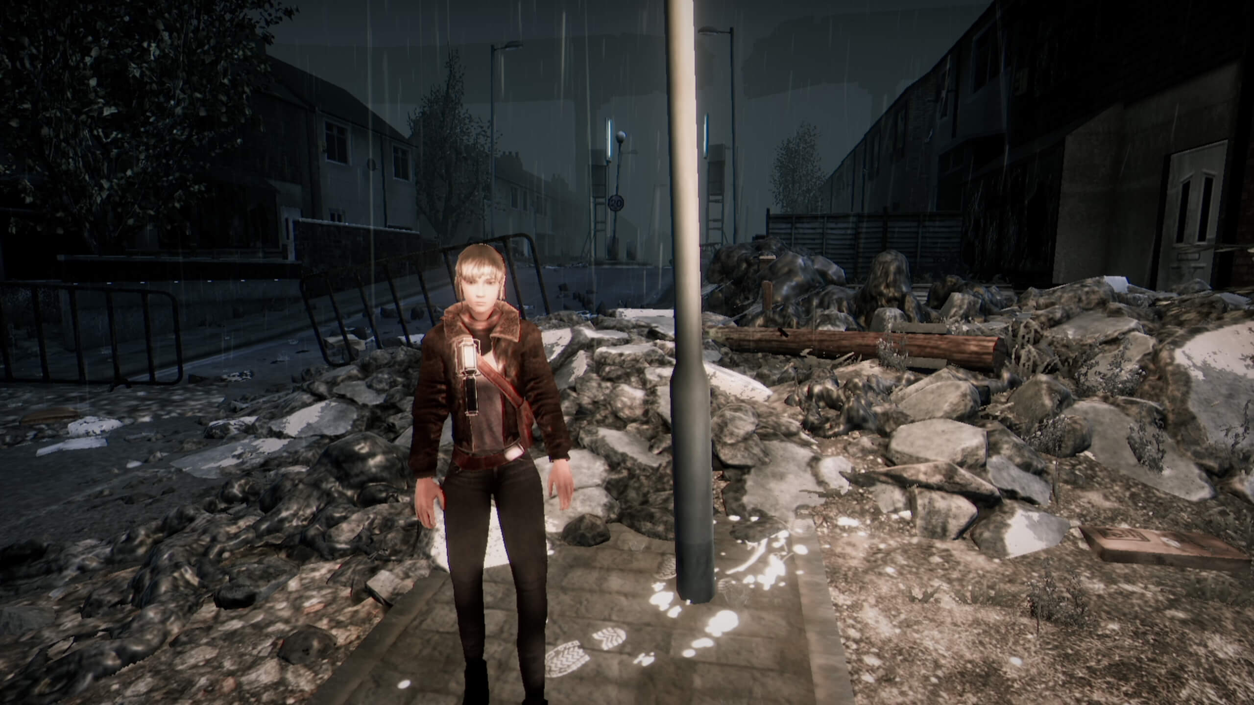 Mica stood next to some rubble looking at the camera, she has mousy blond hair with bangs. She is wearing a leather jacket with the fur collar visible, and a torch attached to her chest. 
