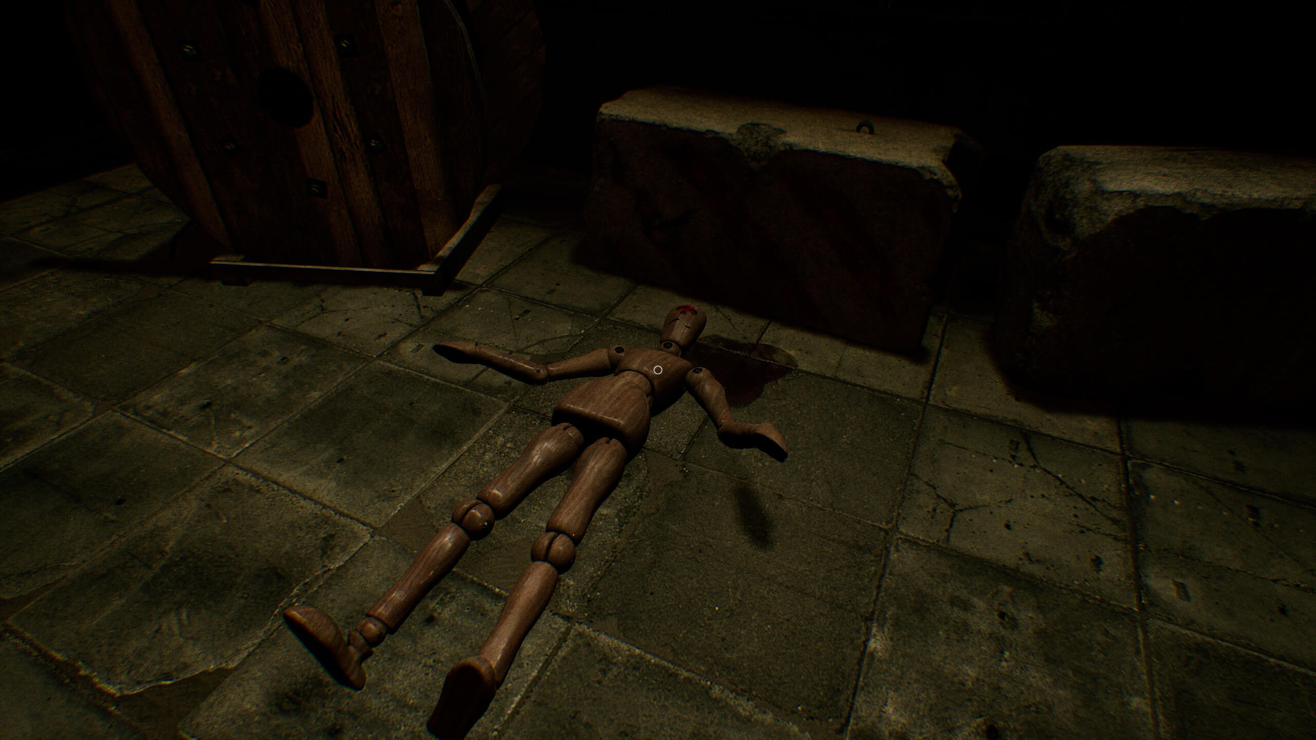 A wooden mannequin laying on the floor with a bullet wound and fake blood around it.