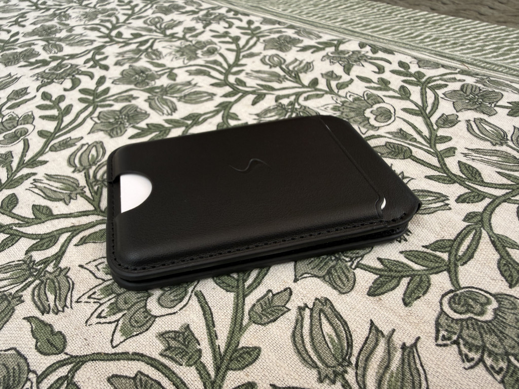 A sleek black leather wallet phone case rests on a patterned tablecloth with green floral designs, exuding a sense of elegance and style.