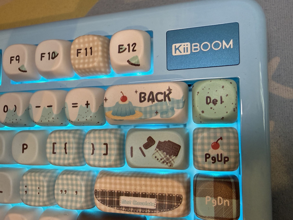 Close-up of blue desert themed kiiboom phantom 81 lite mechanical keyboard with cherry dessert and mint chocolate keycap designs and blue backlighting.