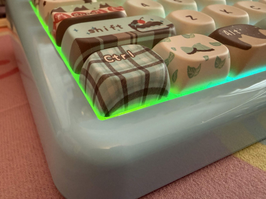 Close-up of blue desert themed kiiboom phantom 81 lite mechanical keyboard with cream dessert and tartan check keycap designs and green rgb backlighting.