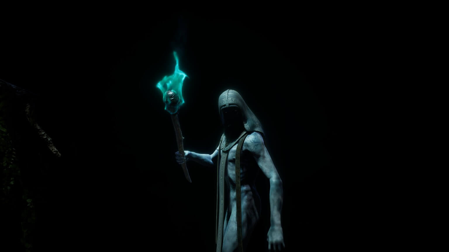 A man stood in a dark forest wearing nothing but a hooded garment that has cloth going down to cover is genitals. He is seen holding a torch with a blue flame.