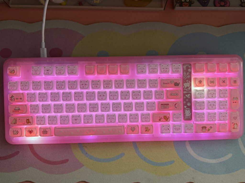 KiiBOOM Phantom 98 Lite pink backlit mechanical keyboard with cute cat face keycaps and additional cartoon character key designs on some keys.