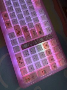 KiiBOOM Phantom 98 Lite pink backlit mechanical keyboard with cute cat face keycaps and additional cartoon character key designs on some keys.