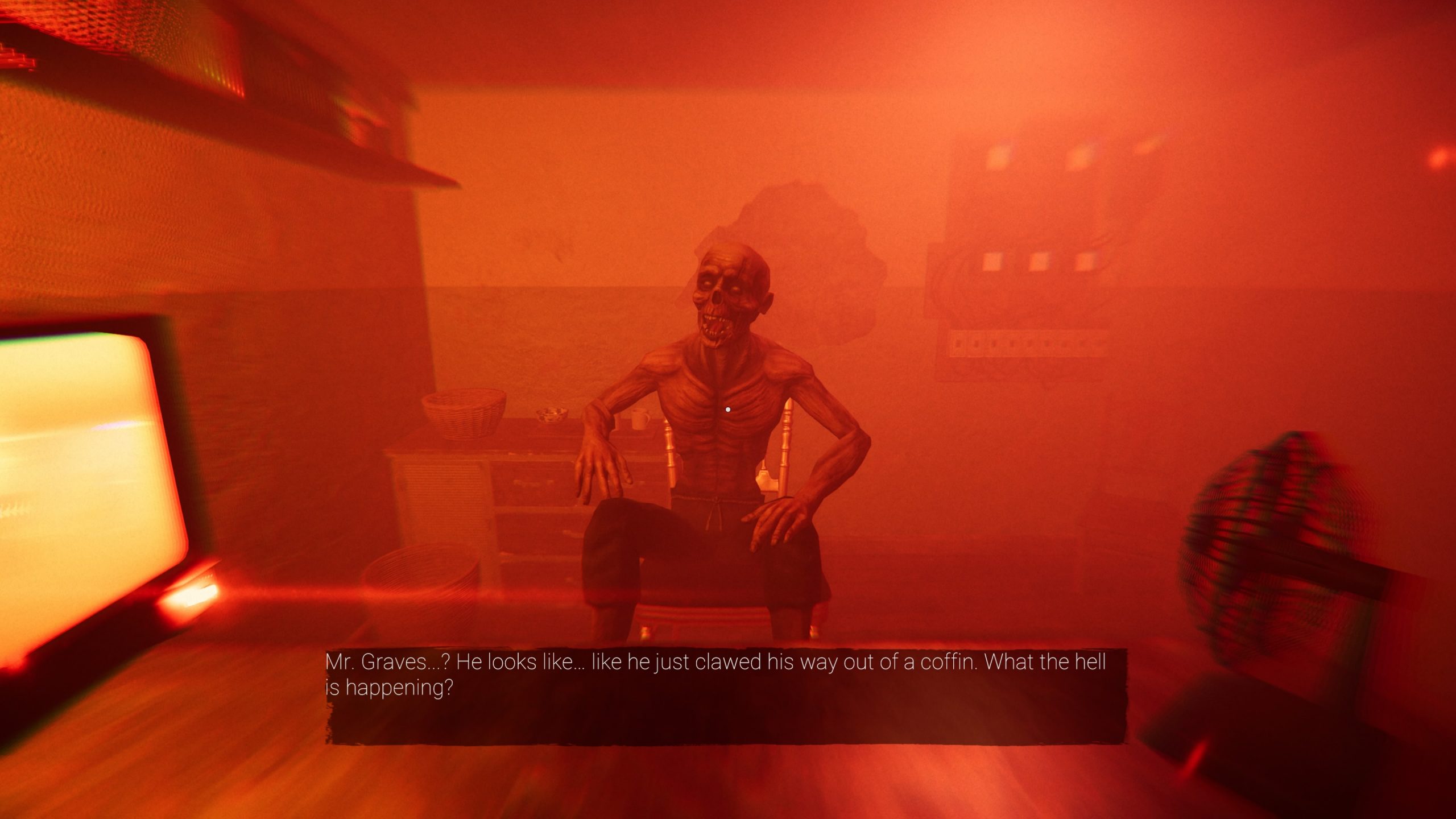 A zombie is sat on a chair with its hands bent holding its knees while the jaw is left open. The whole room has a red hue over it.