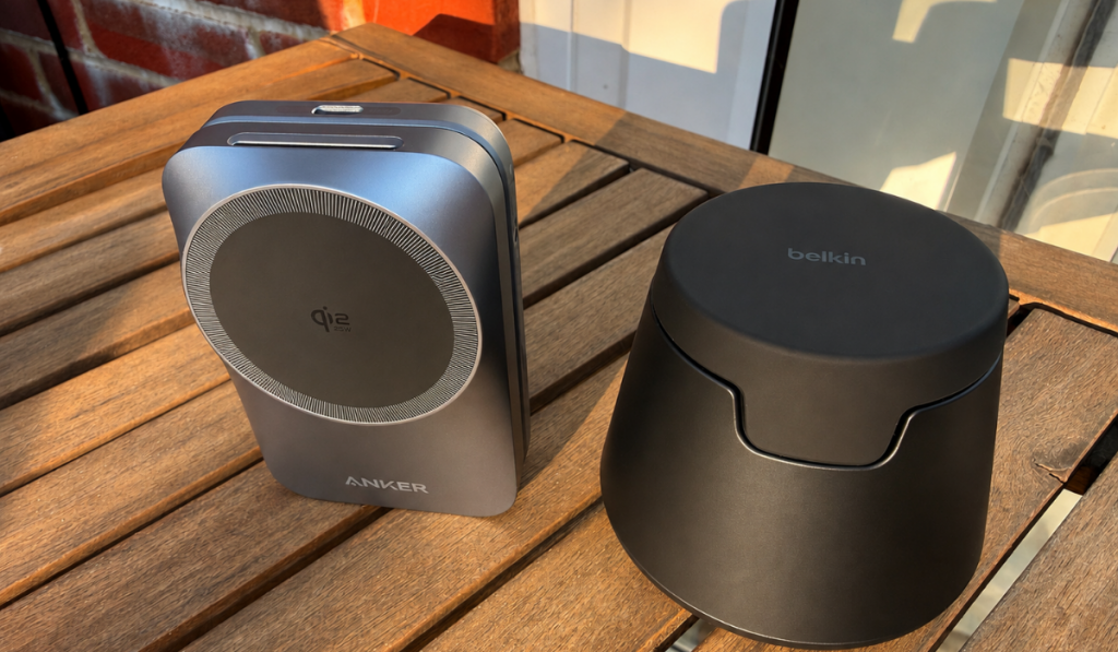 Two compact wireless chargers, a sleek Anker model and Belkin device, sit on a sunlit wooden table, creating a modern, calm scene.