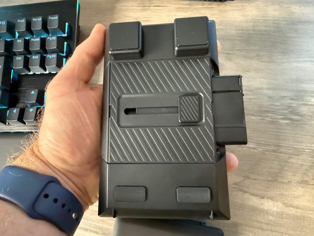 A person holds a black numpad module, showcasing the detachable numpad for flexible use. A slidable button is shown that allows the plug to move to either side of the unit.