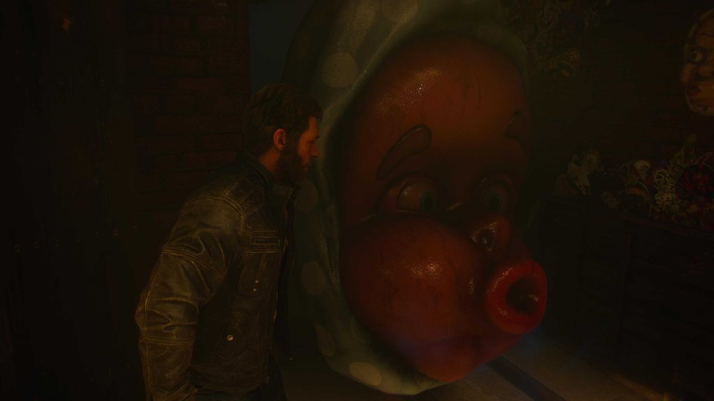 Bearded man in a leather jacket sits beside a woman on a red couch in a dimly lit room.