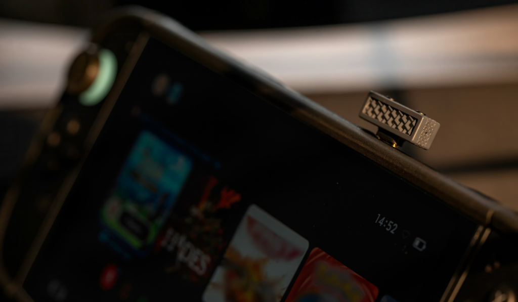 Close-up of a dark nintendo switch with colorful app icons on its screen and a small exposed metal iFi UP Play DAC installed in the USB socket ont he top, creating a technical mood.