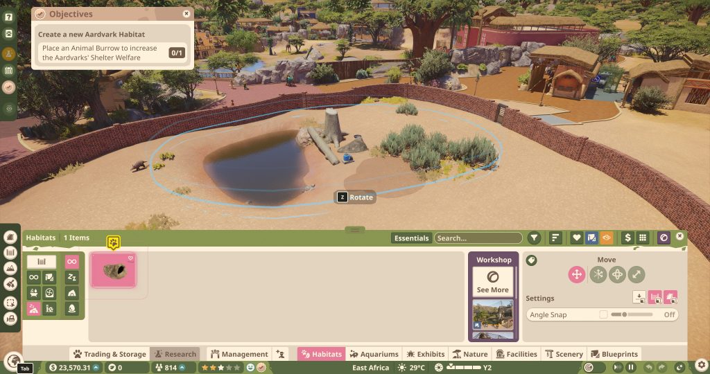 A building game interface shows a sandy park with a pond, shrubs and stone feature, bordered by paths and low buildings; landscaping tools are open.