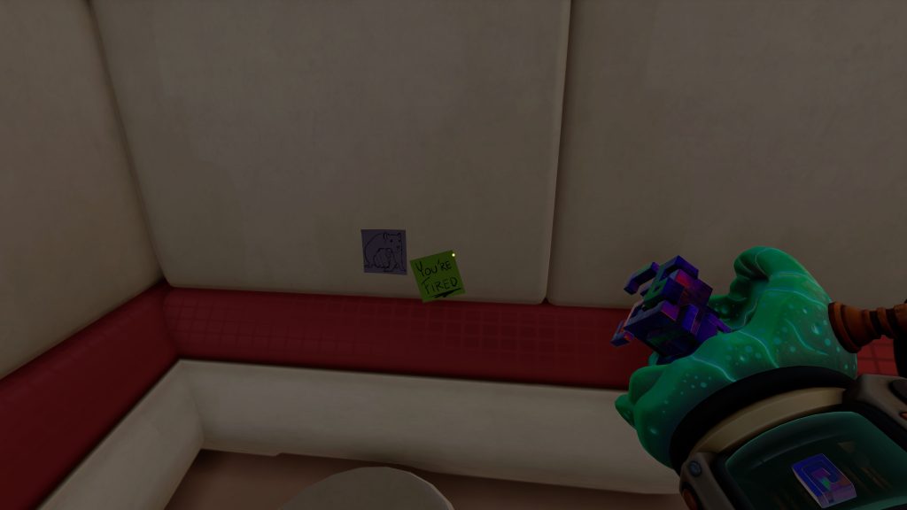 First-person game view of a corner with cat artwork and a “YOU’RE FIRED” note; a green-gloved character holds a weapon.